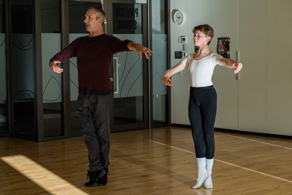 Ballet tutor demonstrating port de bras to a young male student in a Papa Hou studio